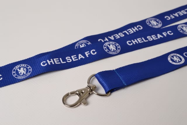 Blauwe polyester lanyard met witte opdruk en musketonhaak, close-up