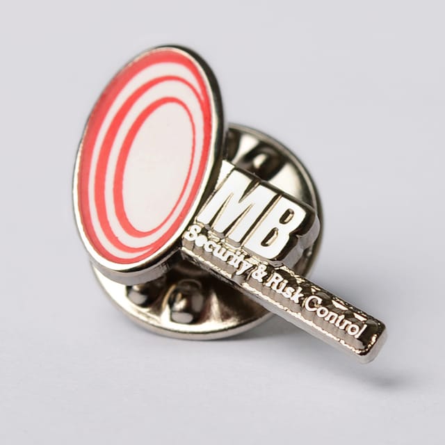Pin met een rond rood-wit logo en letters, van opzij