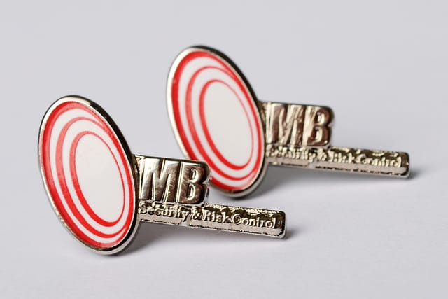 Twee pins met een rond rood-wit logo en letters