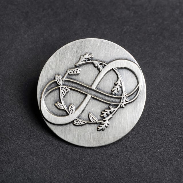 Ronde blank metalen pin met een sierlijk symbool, in antiek zilver