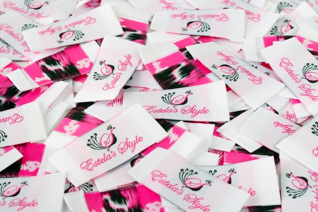 Stapel geweven kledinglabels in roze en wit met een merklogo