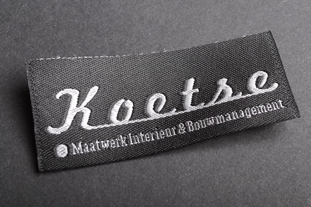 Geweven kledinglabel in zwart met witte sierletters