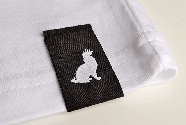 Zwart geweven label met een wit logo, ingenaaid in een wit shirt