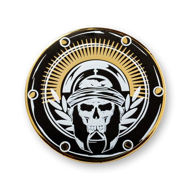 Ronde hard emaille pin in zwart en goud met een doodshoofd en extra witte opdruk