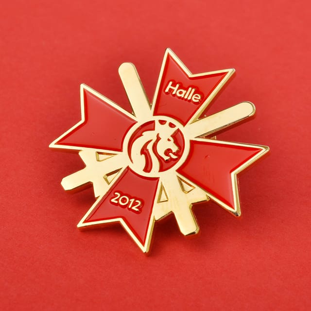 Goudkleurige jubileumpin in stervorm met rood emaille en jaartal