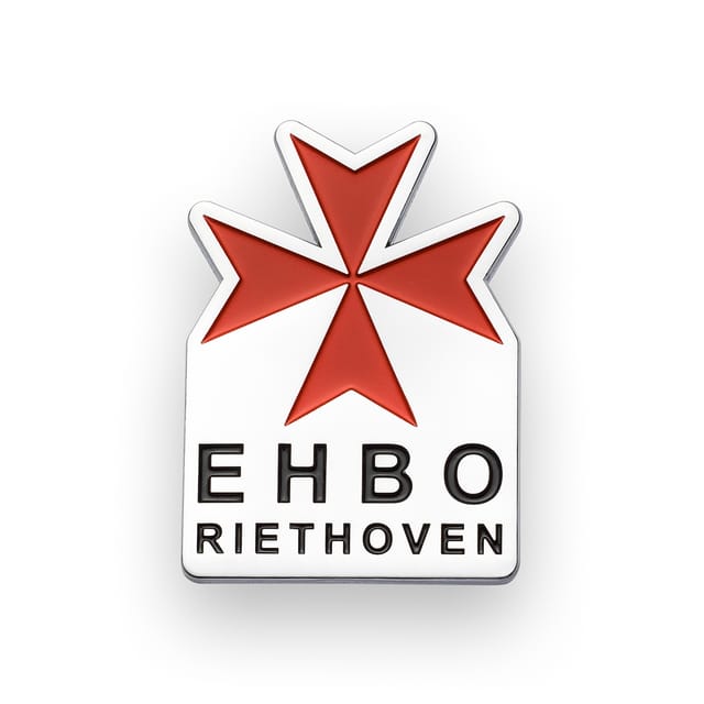 Speldje met een rood kruis en tekst, in chroom