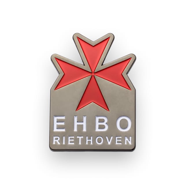 Speldje met een rood kruis en tekst, in zwart nikkel