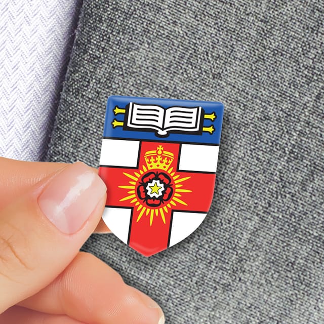 Spoed full colour speldje met een wapen, tussen duim en vinger